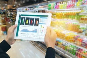 A grocery employee uses an ipad showing analytics in a grocery store.